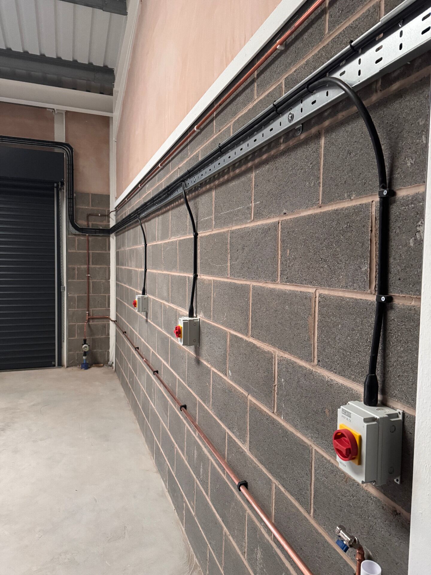 Commercial first-fix electrical installation with cable tray, conduit and rotary isolators