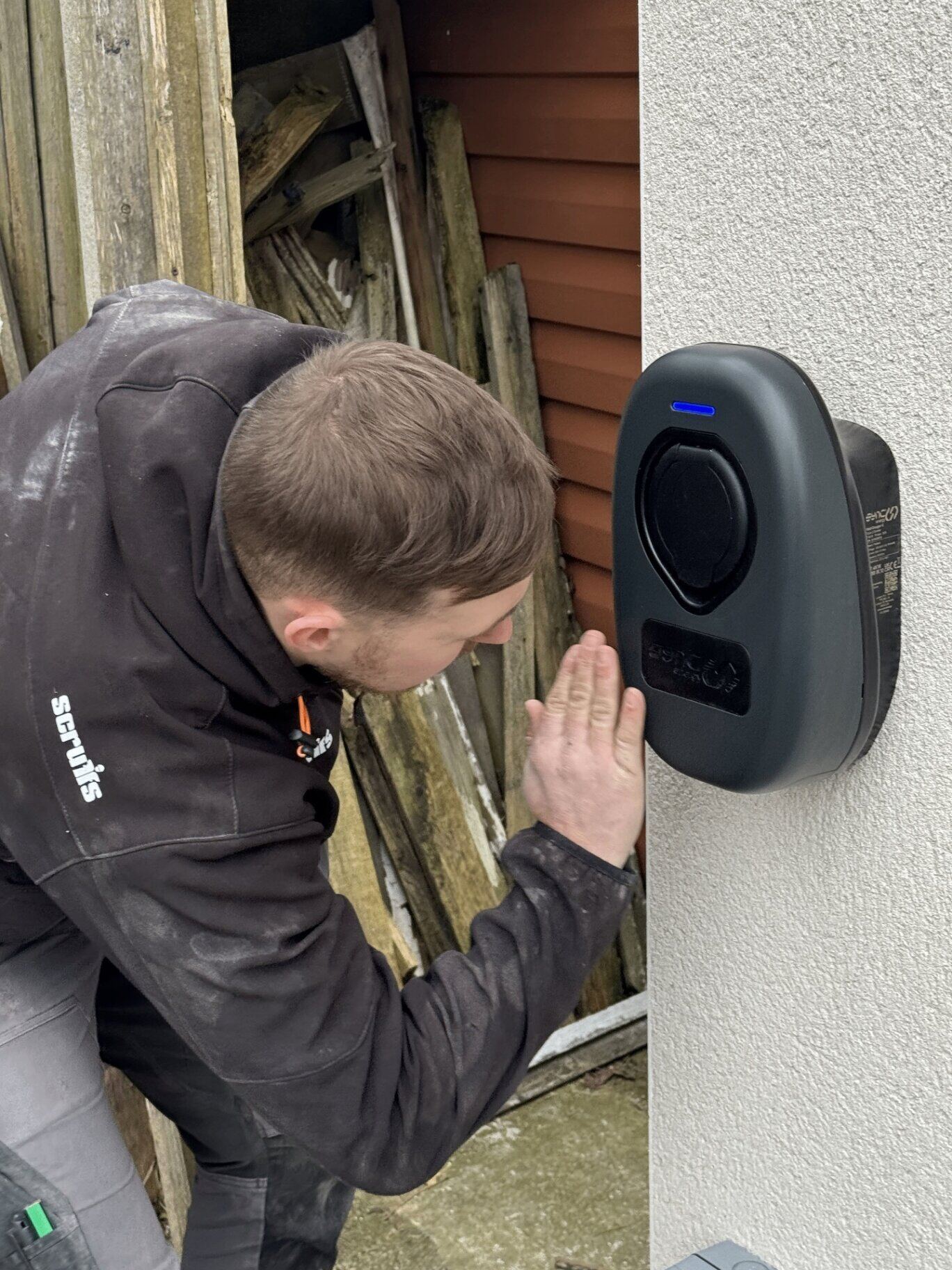 Northern Tec electrician commissioning a Sync Energy domestic EV charge point on a rendered home exterior